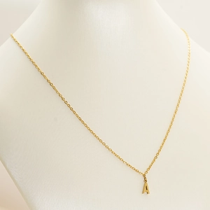 Close-up of golden letter A pendant necklace with polished stainless steel finish
