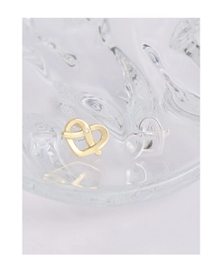 Detail of silver and gold heart-shaped stud earrings with small zircon on glass surface