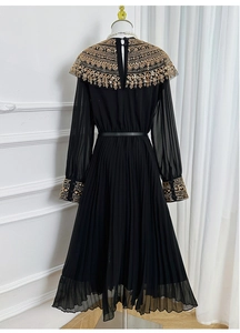 Detailed view of the gold sequined collar and beadwork on the black pleated dress