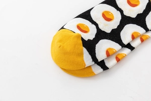 Close-up of black cotton low-cut sock featuring fried egg patterns and yellow toe detail