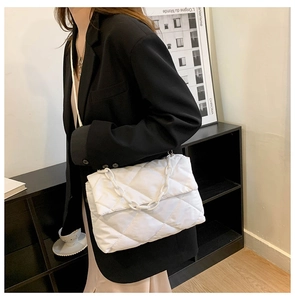 Detailed close-up of a white quilted crossbody bag with stylish thick chain shoulder strap