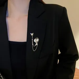 Détail d'une broche fleur et papillon avec de longs glands sur une veste noire