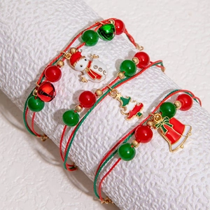 Detail of handmade Christmas bracelets with bells and snowman charms on a textured display