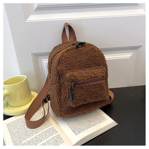Nahaufnahme eines braunen Plüsch-Minirucksacks auf einem Buch mit weichem Fleece-Stoff