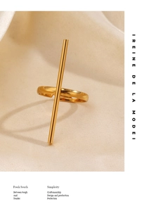 Détail d'une bague rayée réglable en acier doré sur un tissu beige texturé élégant