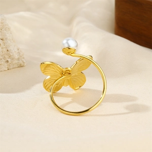 Close-up of vintage gold butterfly ring with pearl and shell flower on soft fabric