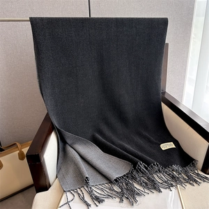 Detail of soft double-sided black and grey cashmere scarf with elegant fringe and tag