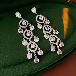 Vintage zircon teardrop tassel earrings in silver tone displayed on green velvet