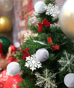 Close-up of mini Christmas tree with white snowballs and festive red ribbon bows