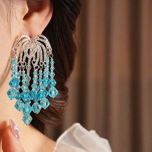 Close-up of elegant silver tassel earrings with blue faceted crystal beads on model