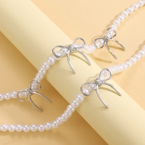 Collier de perles avec nœuds argentés présenté sur un support cylindrique élégant