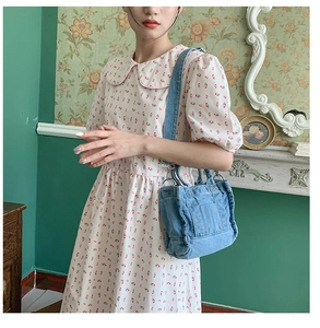 Close-up of a blue washed denim tote bag styled by a model in a retro interior setting