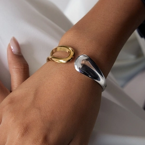 Detailed view of two-tone gold and silver open cuff bracelet with sculpted droplet design
