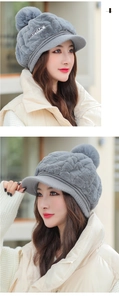 Detail of grey winter plush knit cap featuring a peak brim and large fluffy pompom