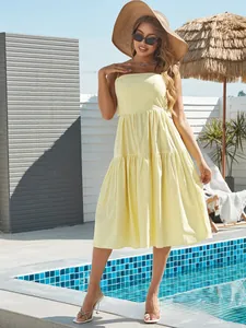 Detail of tiered yellow sun dress with spaghetti straps against a resort background