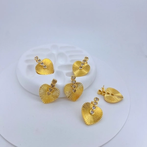 Macro shot of gold heart earrings with sunburst texture and micro-inlaid zircon stones