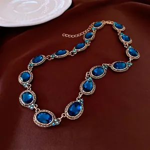 Collier vintage en or avec pierres bleues ovales et diamants émeraude sur satin brun