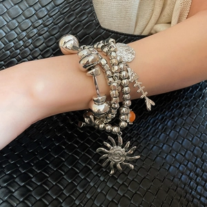 Detail of layered bohemian silver bead bracelets with sun and shell charms on model wrist