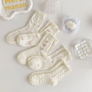 Flat lay of five pairs of cream white Lolita style socks with bows and lace ruffles