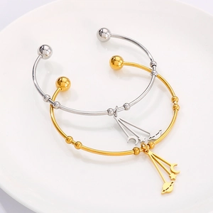 Minimalist moon and star celestial bangles in gold and silver finish on a ceramic plate