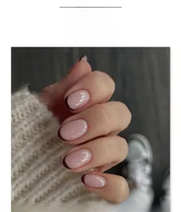 Close-up of short round press-on nails with pink base and deep red French tips