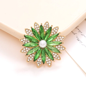 Élégante broche fleur dorée avec cristaux verts et centre perle blanche sur plateau