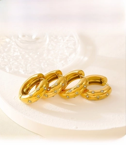 Detailed view of gold PVD plated hoop earrings with starburst engraving and crystals