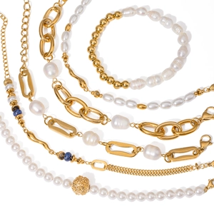 Set of gold stainless steel bracelets with pearls and blue beads on white background