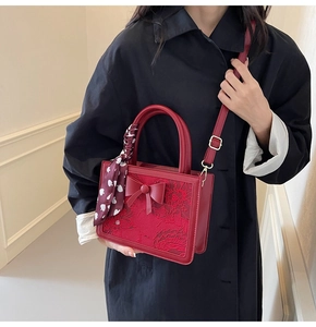 Detail of red bridal handbag with floral embroidery, silk scarf, and 3D bow accent