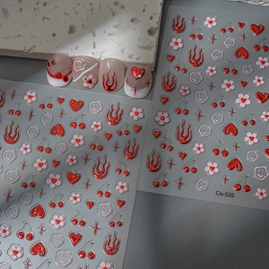 Detailed view of red metallic nail stickers with heart and flame patterns, style Co-535