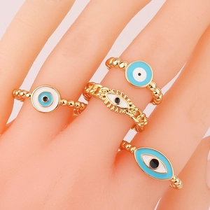 Detailed set of four gold evil eye rings with blue enamel on a mannequin hand