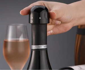 Detail showing hand locking a black champagne stopper on a moscato wine bottle