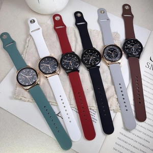 Six quartz sport watches with silicone straps in various colors on a beige linen background