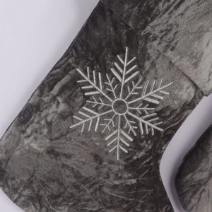 Detailed view of gray velvet Christmas stocking with white snowflake embroidery texture