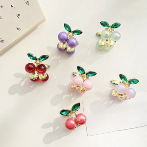 Mini alloy cherry hair claws in six vibrant colors with gold leaf accents on beige background