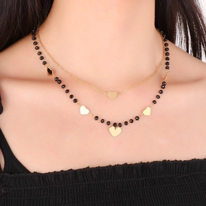 Close-up of double layer necklace with black beads and gold heart pendants on model