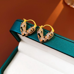 Detailed macro view of leopard print heart earrings on a dark green jewelry box