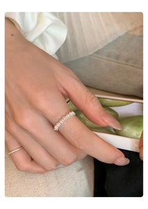 Detail of silver bow and pearl open ring with woven texture worn on finger