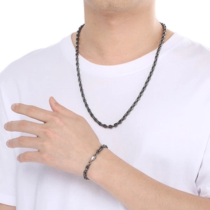 Gros plan d'un ensemble collier et bracelet en acier inoxydable noir sur un mannequin