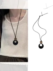 Minimalist long resin ring pendant necklace with black cord on white sweater