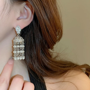 Detailed close-up of vintage tassel earrings with silver finish, diamonds, and white pearls