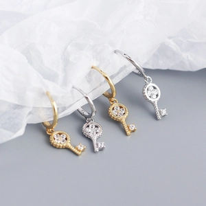 Detailed view of silver and gold clover key earrings with sparkling zircon inlay