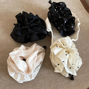 Détail de quatre pinces à cheveux en tissu plissé beige et noir à pois rétro