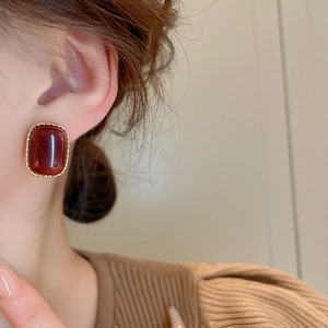 Detail view of retro gold-plated square studs with red resin inlay on a model