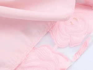 Détail de la dentelle brodée de fleurs roses sur l'ourlet de la robe courte taille haute