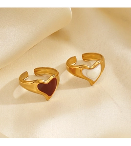Close-up of gold-plated heart rings on beige silk, featuring red and white enamel detail