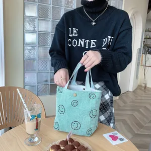 Detail of mint green corduroy tote bag with smile print and secure magnetic snap button