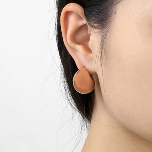 Detail of elegant hollow teardrop earrings in matte 18K gold finish on model