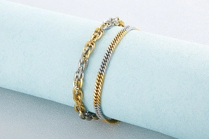 Detail of two-tone gold and silver titanium steel link bracelets on a blue display stand