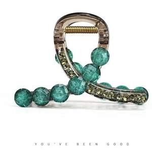 Detailed shot of dark translucent hair claw with marble green beads and yellow rhinestones